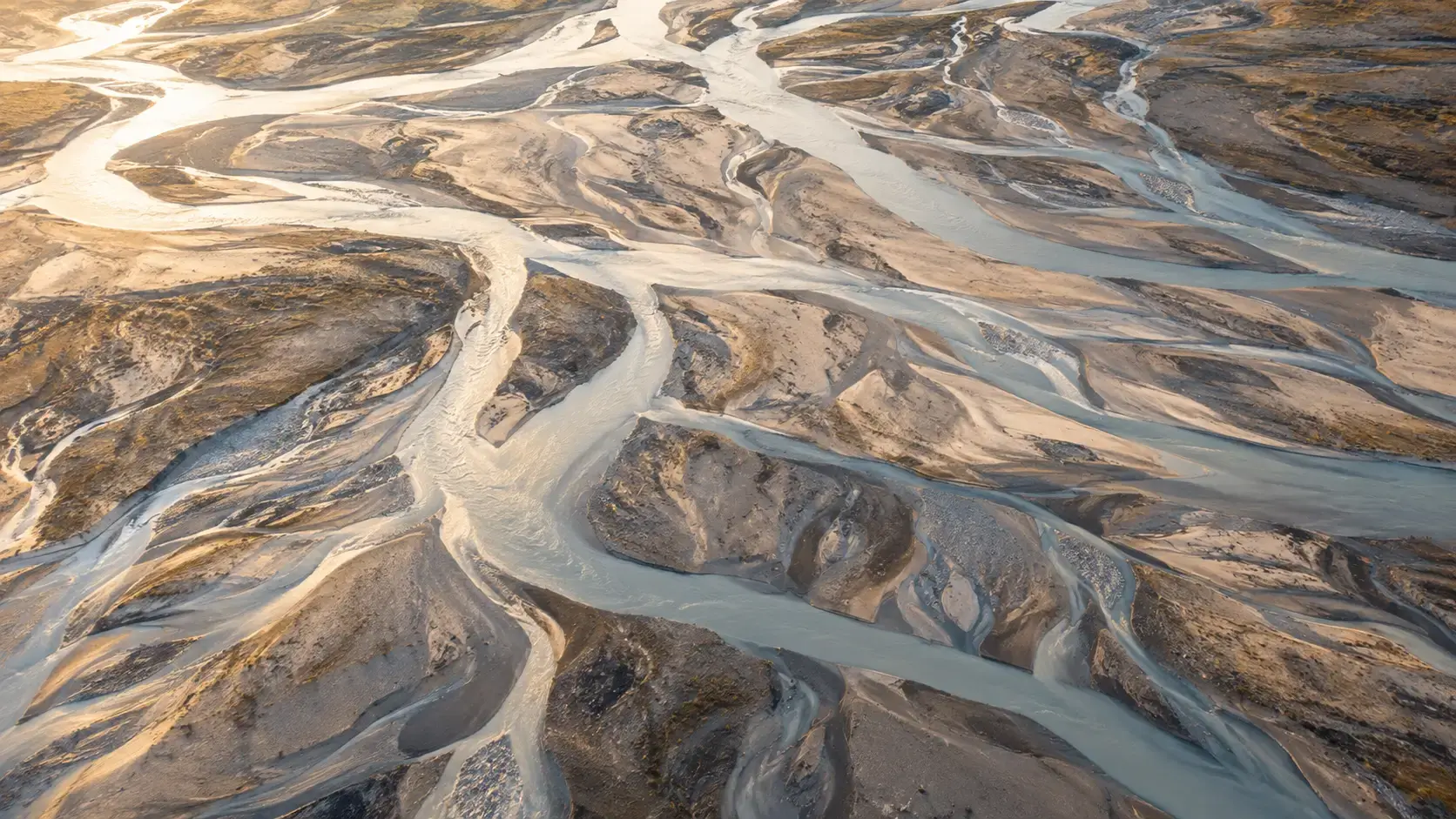 Aerial view of a river carving new channels across sand, illustrating how attachment styles change over time.