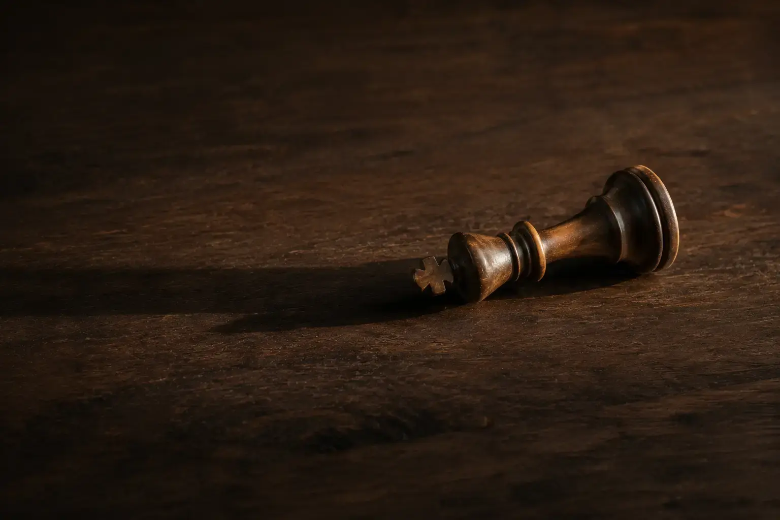 A wooden chess king lying on its side on a dark surface, representing moral injury and the collapse of identity and belief after military service