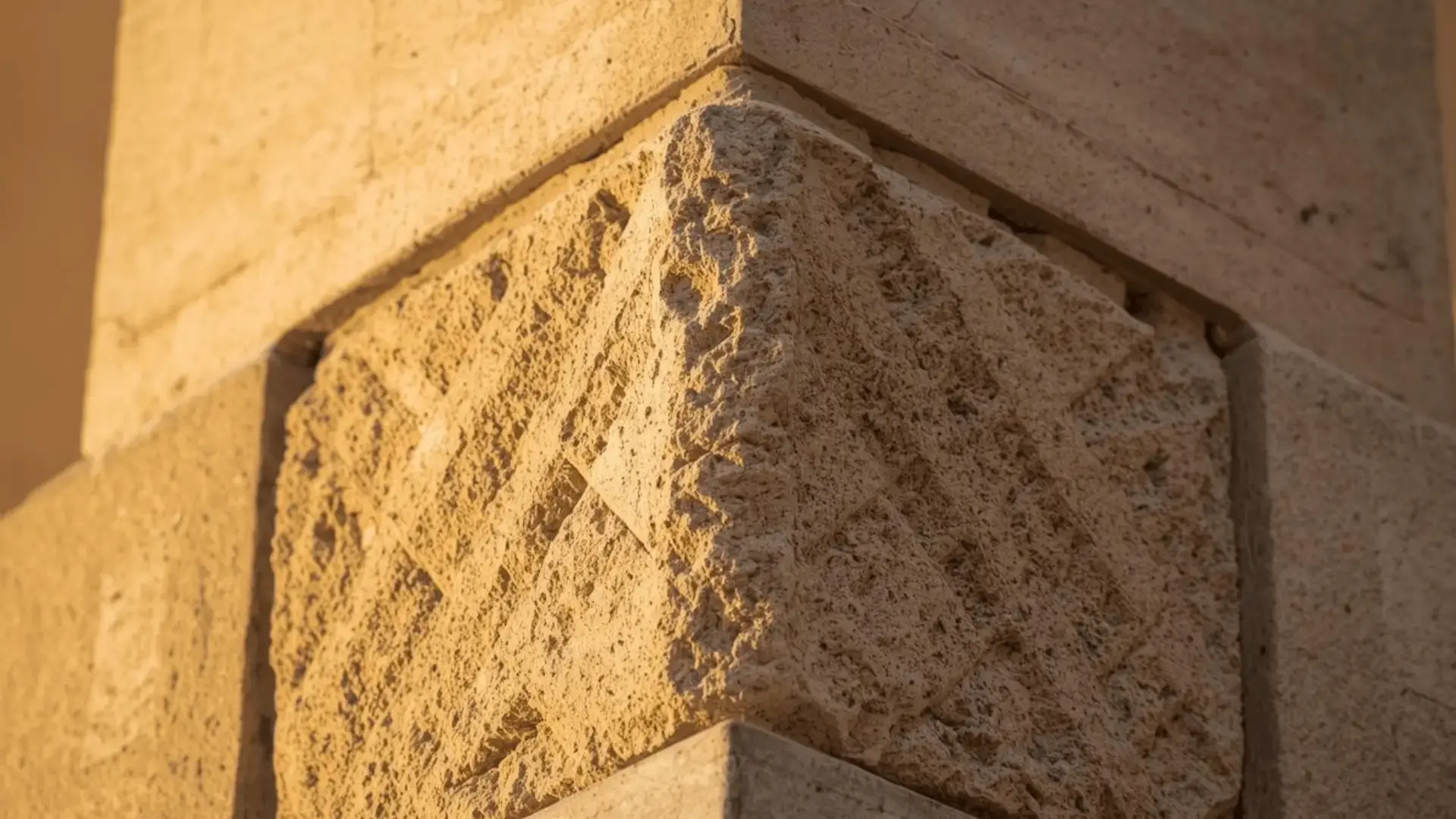 Close-up of a textured cornerstone where two stone walls meet, bathed in warm golden light Trauma Therapist Institute