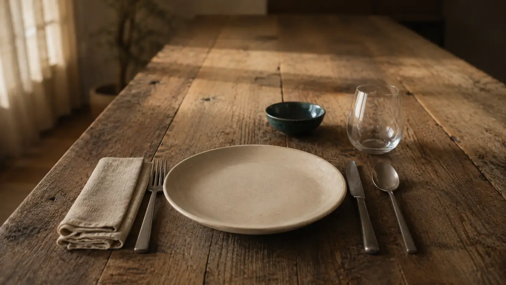 Single dining place setting alone at a long wooden table with soft window light, representing the quiet absence at the heart of emotional neglect