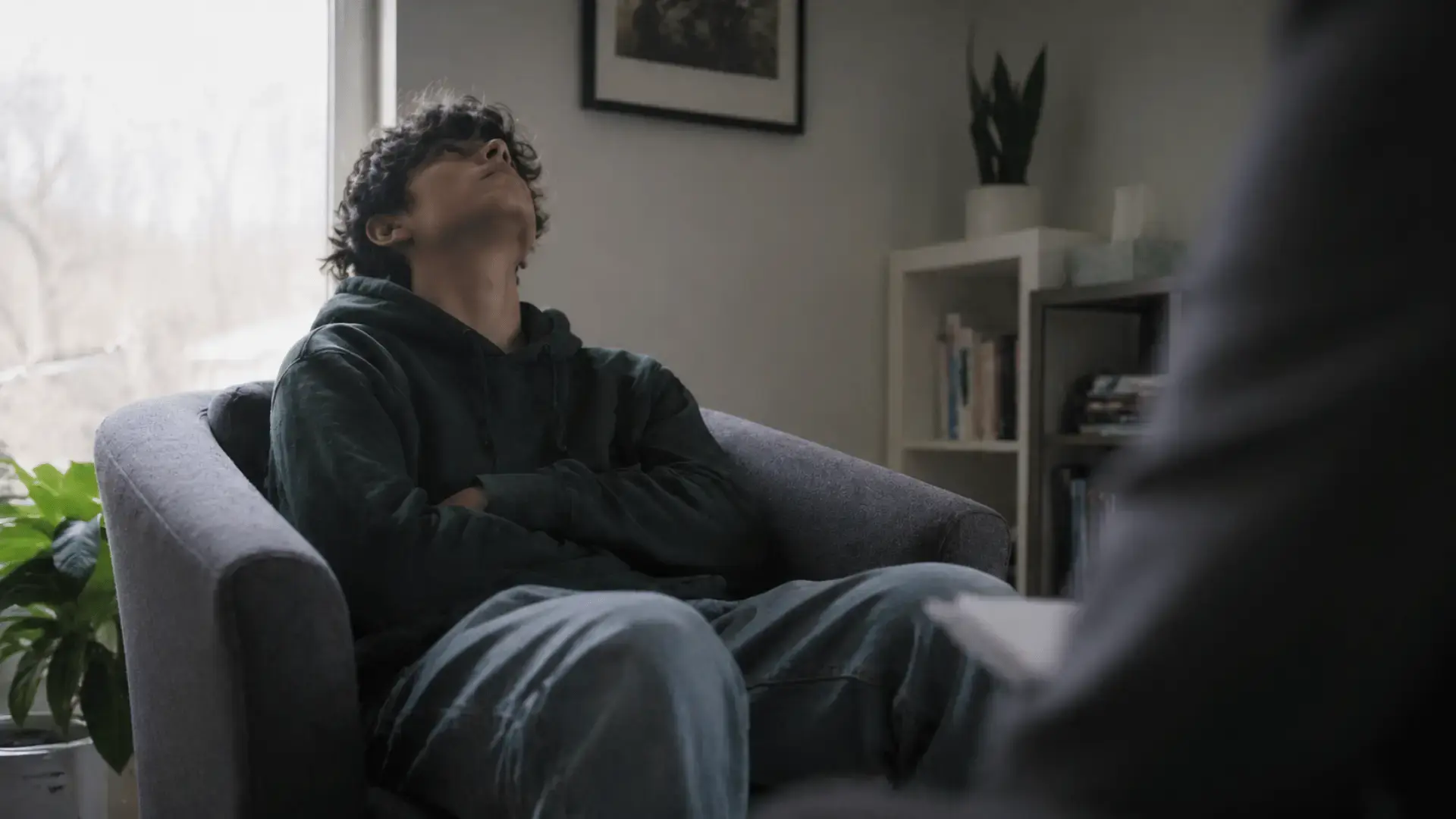A teenager seated in a therapy room, looking at the ceiling with mild boredom or skepticism. Face partially obscured or angled away. The image should land the opening scene of the post (the 14-year-old who said "this is stupid") without being on-the-nose. Natural light, real-feeling rather than staged.